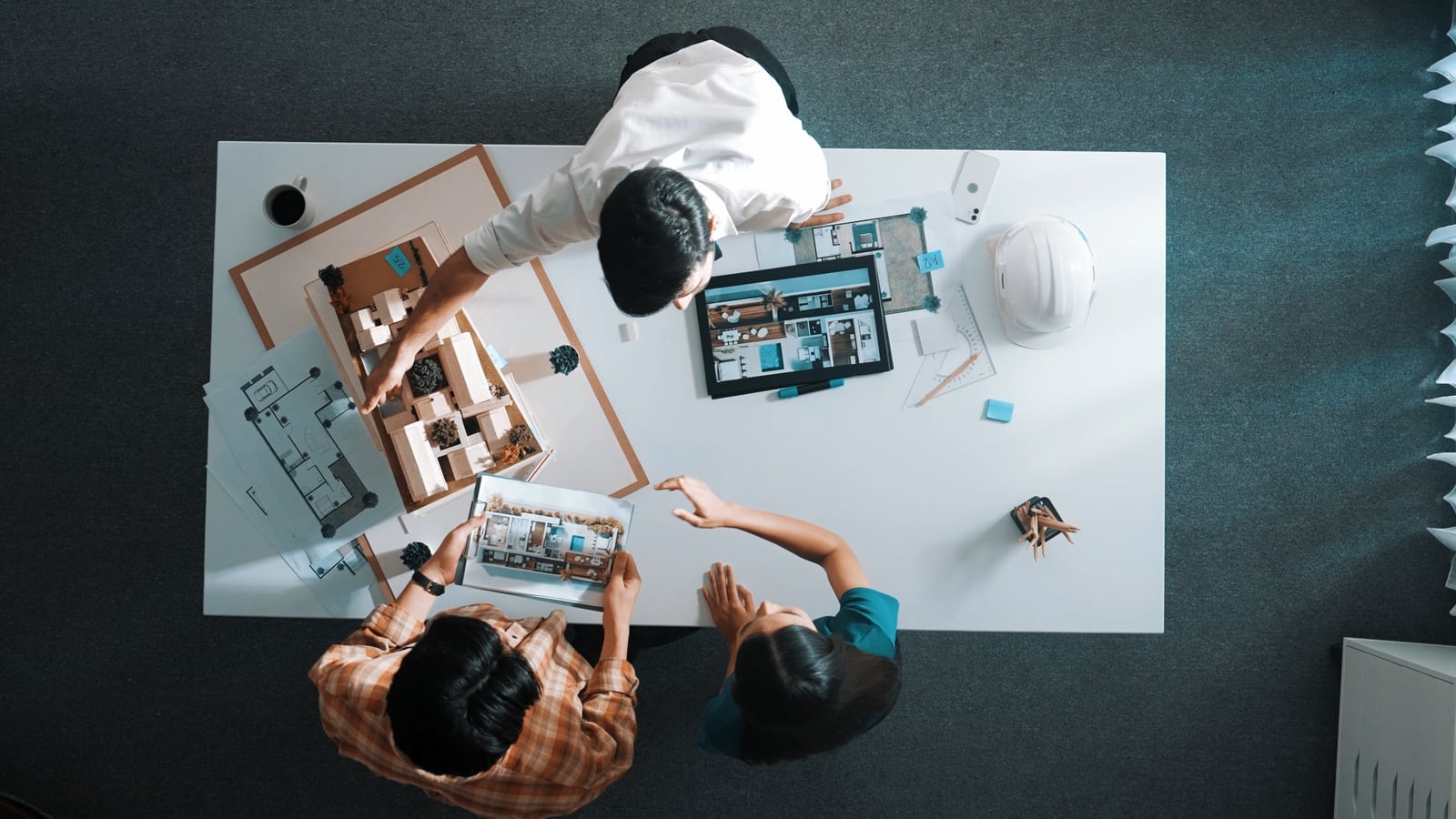 Vue plongeante sur une table de travail : plans, maquettes et échantillons partagés par l’équipe projet.