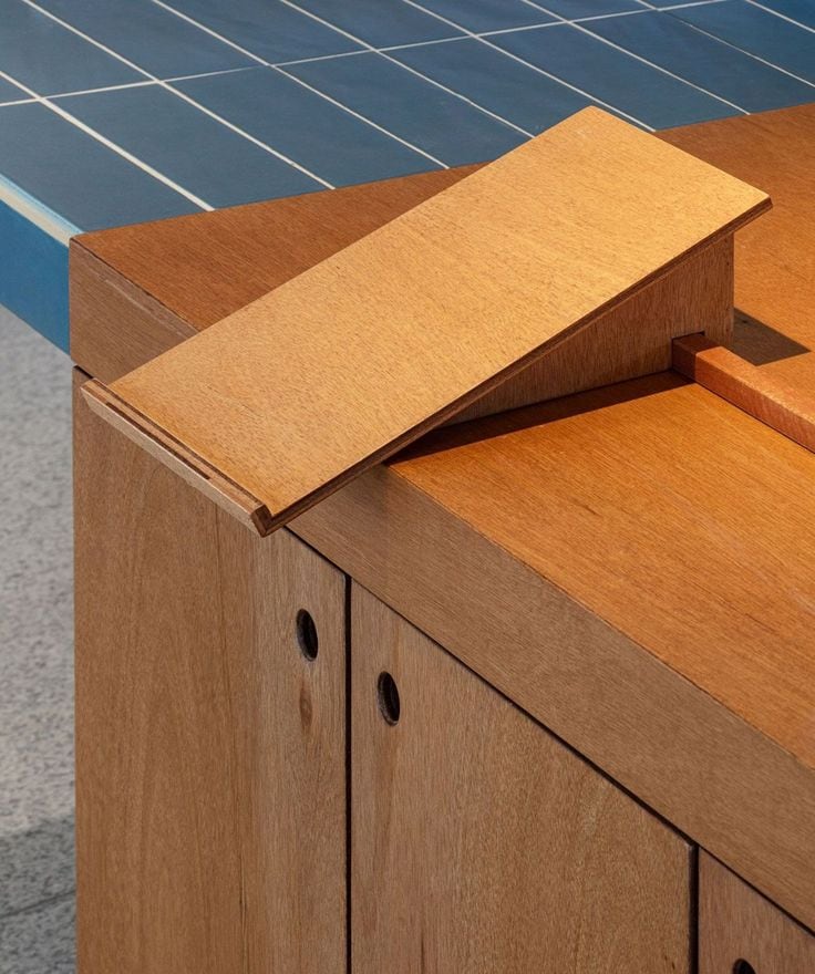 Détail d'un assemblage en bois massif posé sur un plan carrelé bleu.