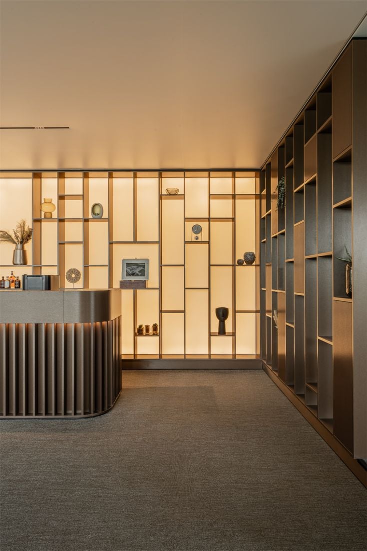 Showroom : comptoir d'accueil et étagères rétroéclairées en bois clair.